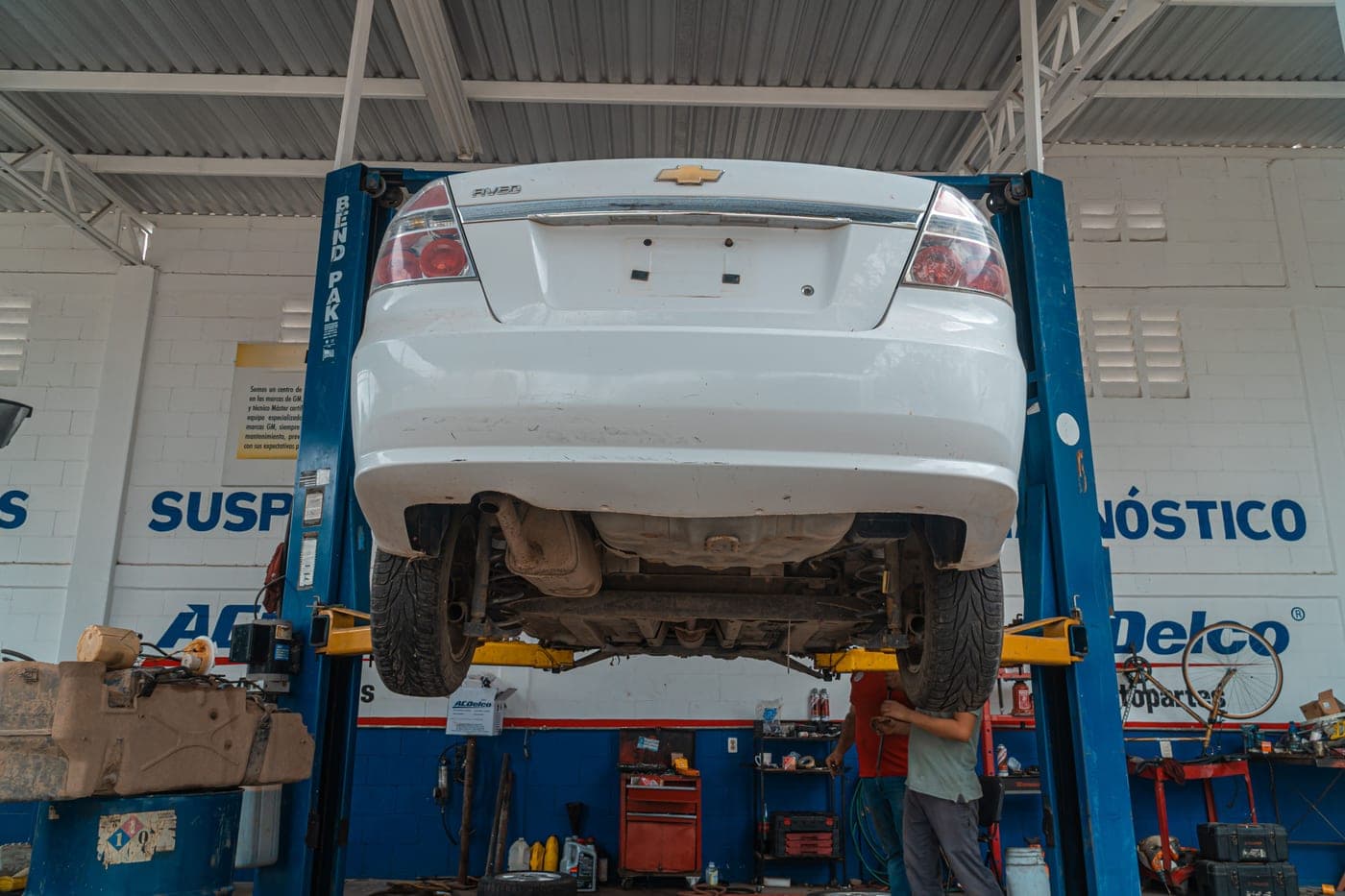 A white car raised for maintenance in an automotive repair shop
