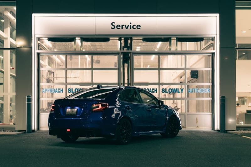 A car at the entrance of a service station lit at night
