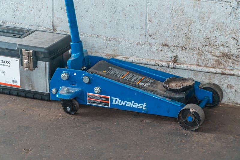 A blue hydraulic floor jack standing beside an open toolbox on a garage floor