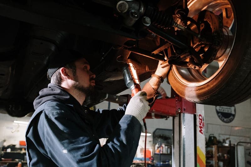 A mechanic examining the underside of a car in a garage