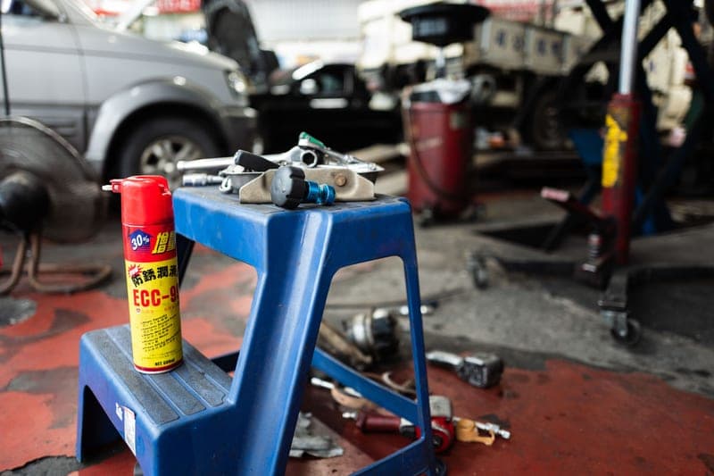 Hand tools and automotive parts laid out on a stool in a repair shop