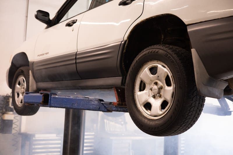 A white car suspended above the floor in an automotive repair shop