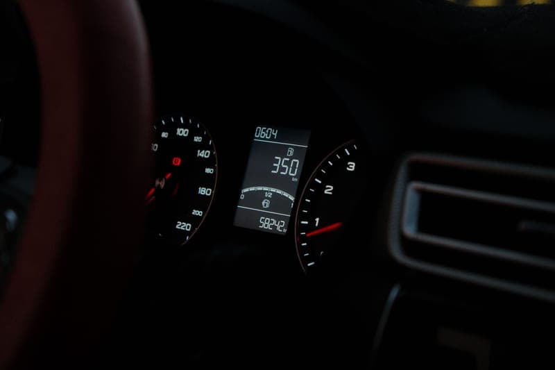 A car dashboard showing the speedometer and digital readout at night