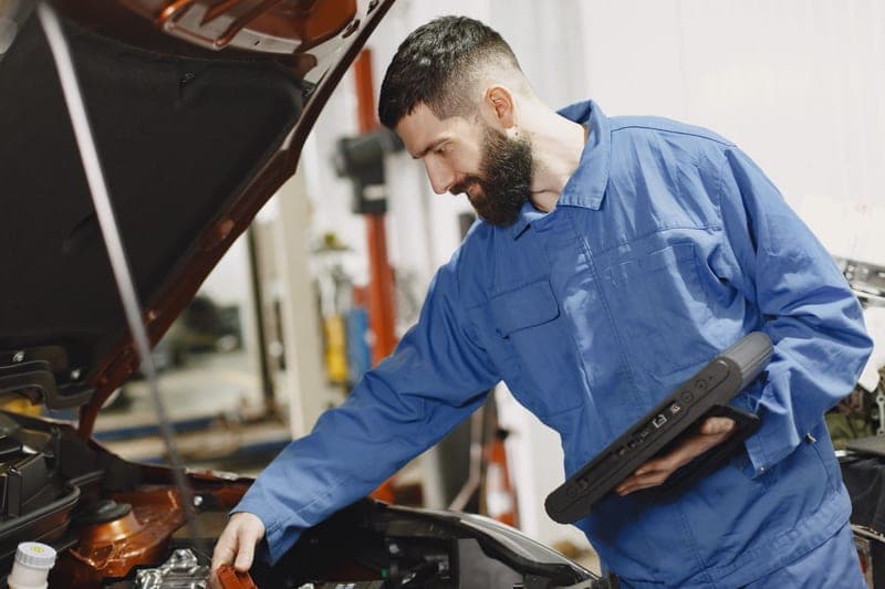 An auto mechanic inspecting a car engine in a garage