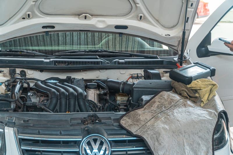 A car engine undergoing repair with diagnostic equipment in use