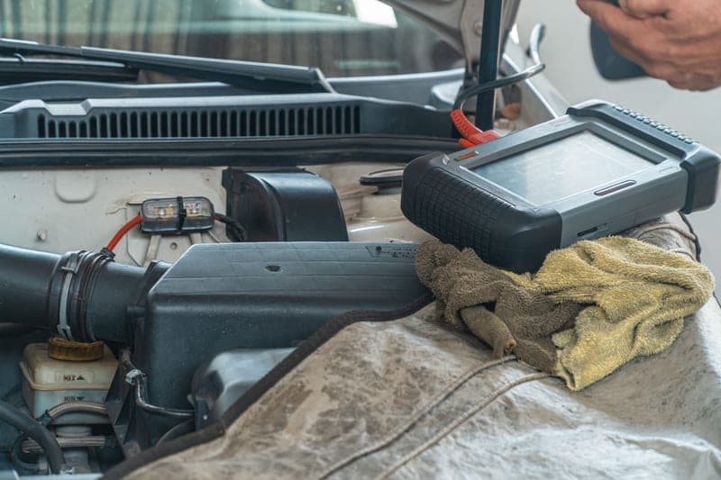 A car engine being inspected with a handheld diagnostic tool