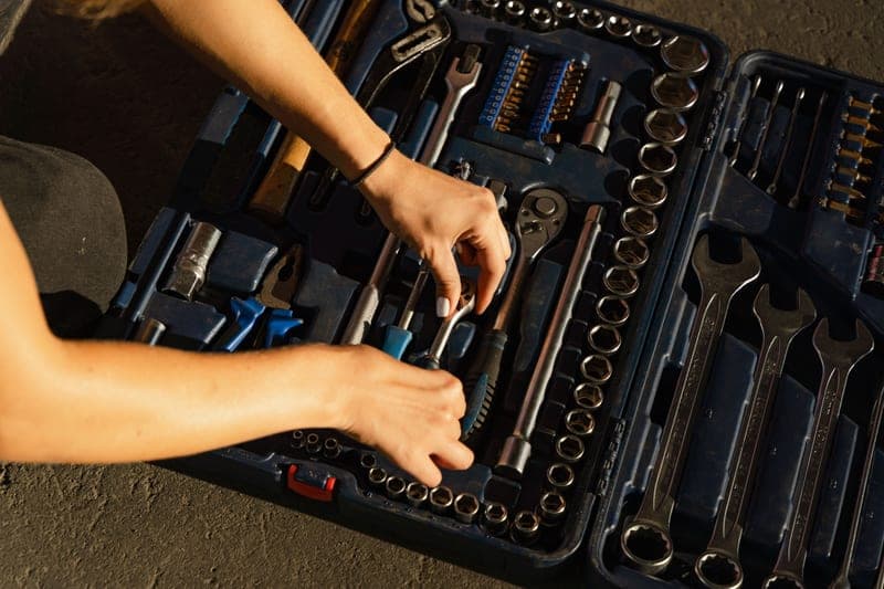 Hands organizing hand tools inside a blue toolbox
