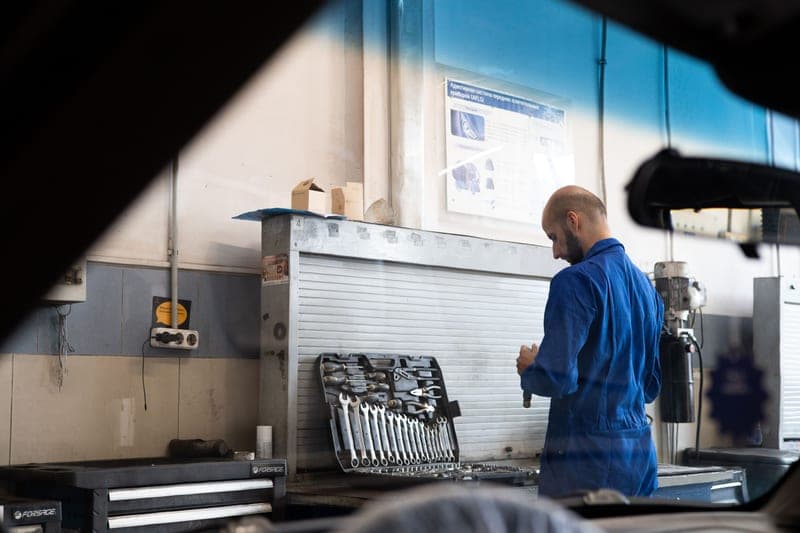 A mechanic in coveralls checking hand tools in an automotive workshop