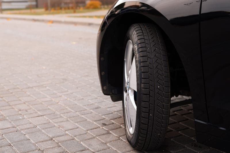 A car tire resting on a cobblestone road