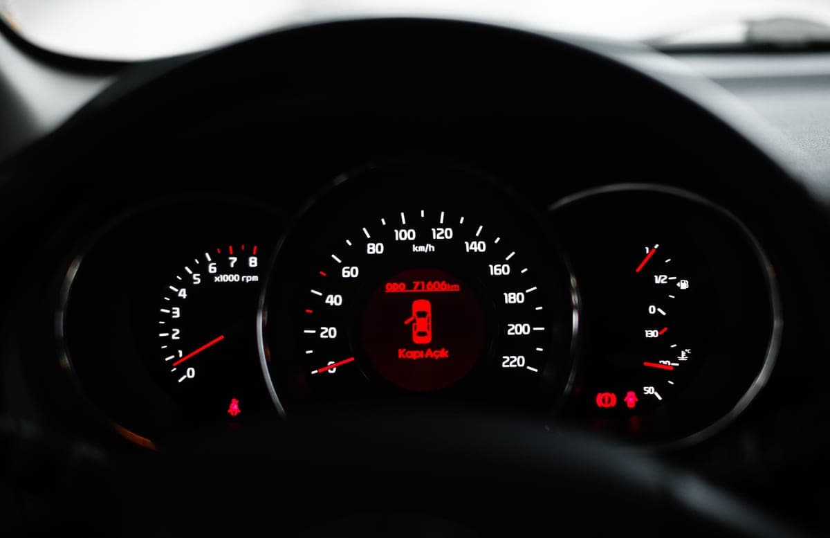 A car dashboard showing a warning light with dials and gauges in focus
