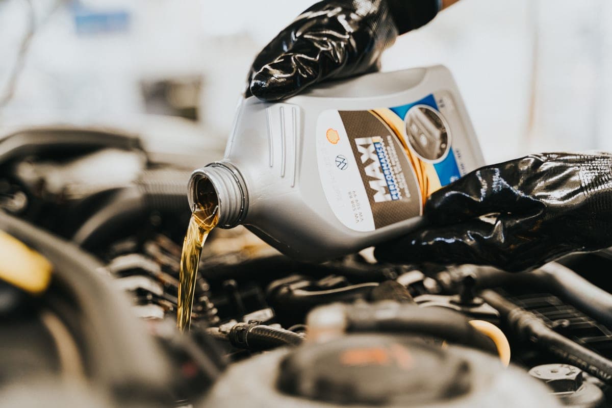A mechanic pouring engine oil into a car engine